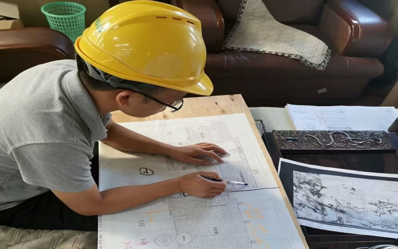 Engineer in hard hat meticulously reviewing construction drawings, ensuring accuracy for stone project implementation